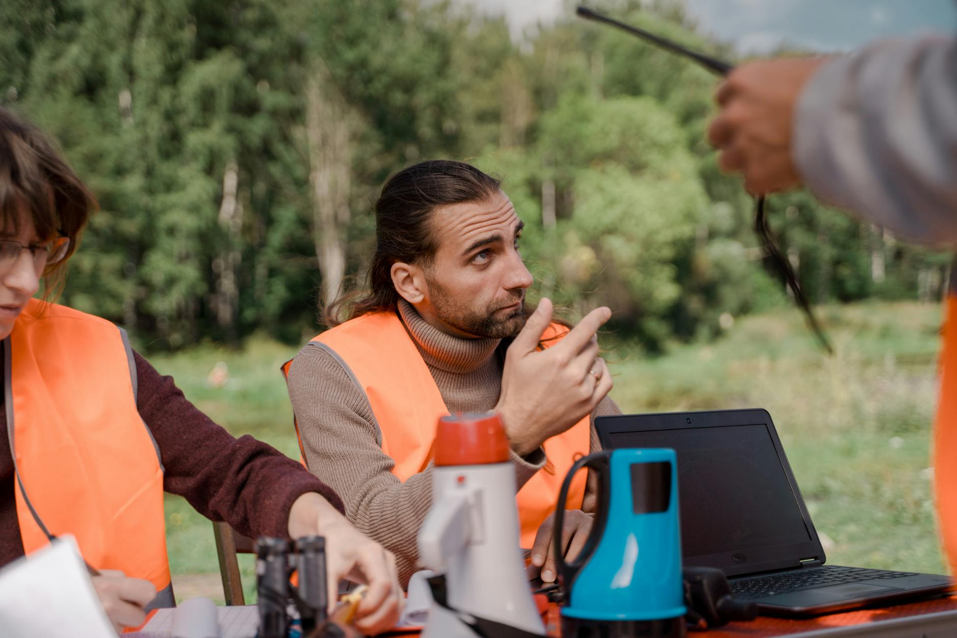 Bénévoles en gilets orange coordonnant leurs efforts avec des ordinateurs portables